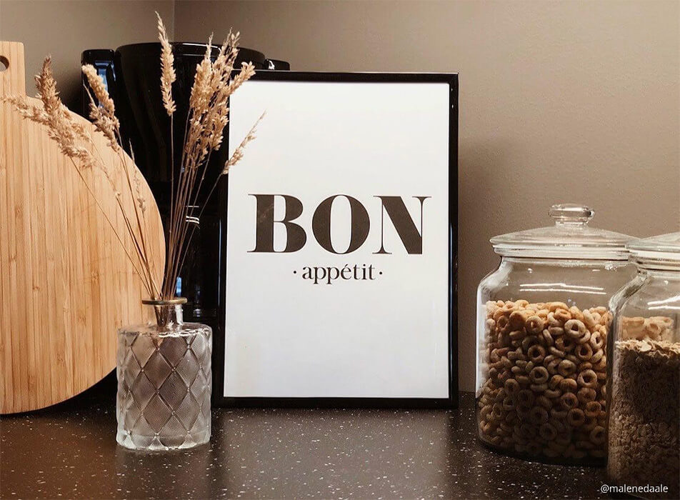 Kjøkkenbilde med teksten Bon appétit, kaffebrygger og glasskrukker på mørk benkeplate