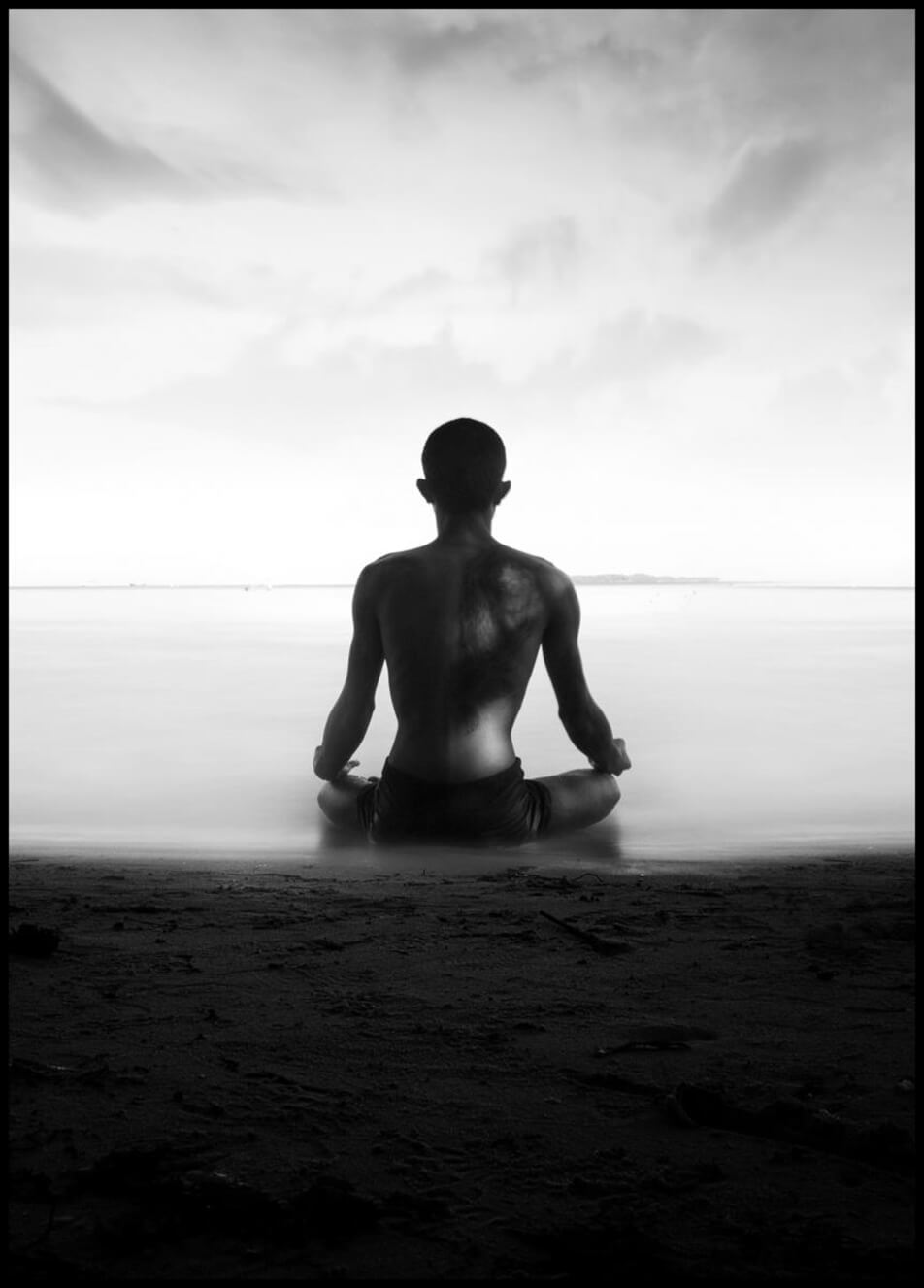 Poster med foto som forestiller en mann som mediterer ved strandkanten